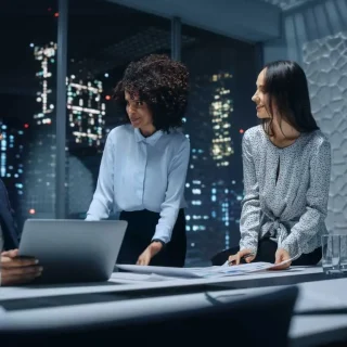 Office Conference Room Meeting: Diverse Team of Top Managers Talk, Brainstorm, Use Laptop Computer. Business Partners Discuss Financial Reports, Plan Operations Based on Line and Pie Graph Reports.