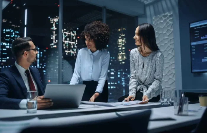 Office Conference Room Meeting: Diverse Team of Top Managers Talk, Brainstorm, Use Laptop Computer. Business Partners Discuss Financial Reports, Plan Operations Based on Line and Pie Graph Reports.