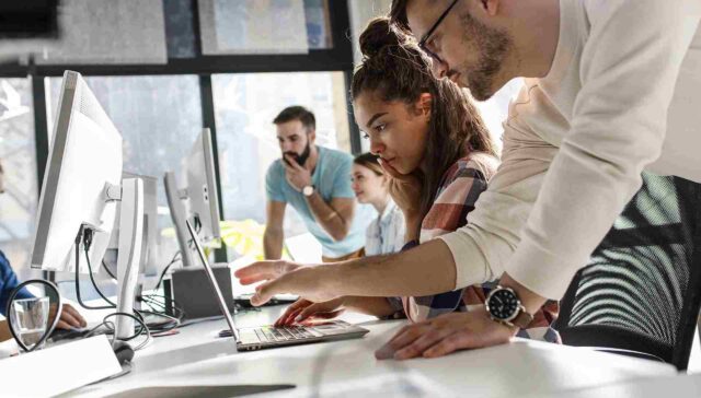 collague point to on laptop, another is watching