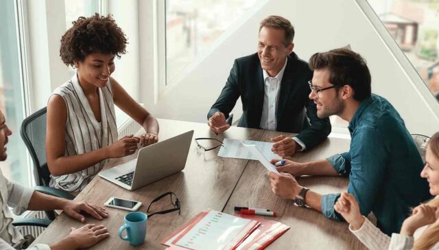 office management talking and laughing on something on a meeting table