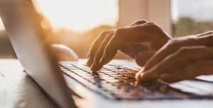 two hand typing something on laptop