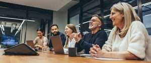 employees laughing on a meeting table during a meeting discussion