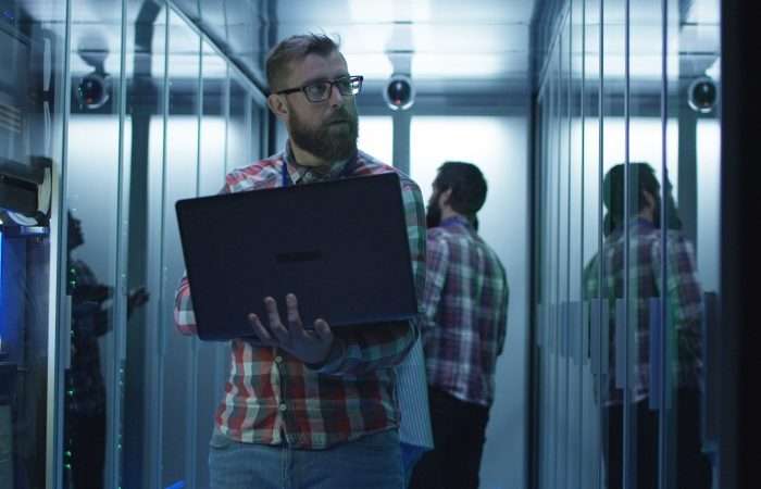 Bearded IT engineer using laptop in server room