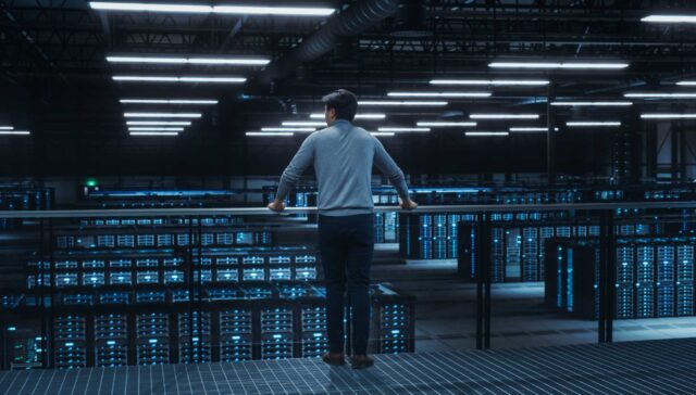 Data Center Engineer Looking Down from a Balcony on Server Farm Cloud Computing Specialist Facility. Multiethnic Asian System Administrator Working with Data Protection Network for Cyber Security